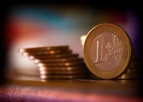A close-up shot of stacked euro coins with a blurred colorful background, representing financial concepts.